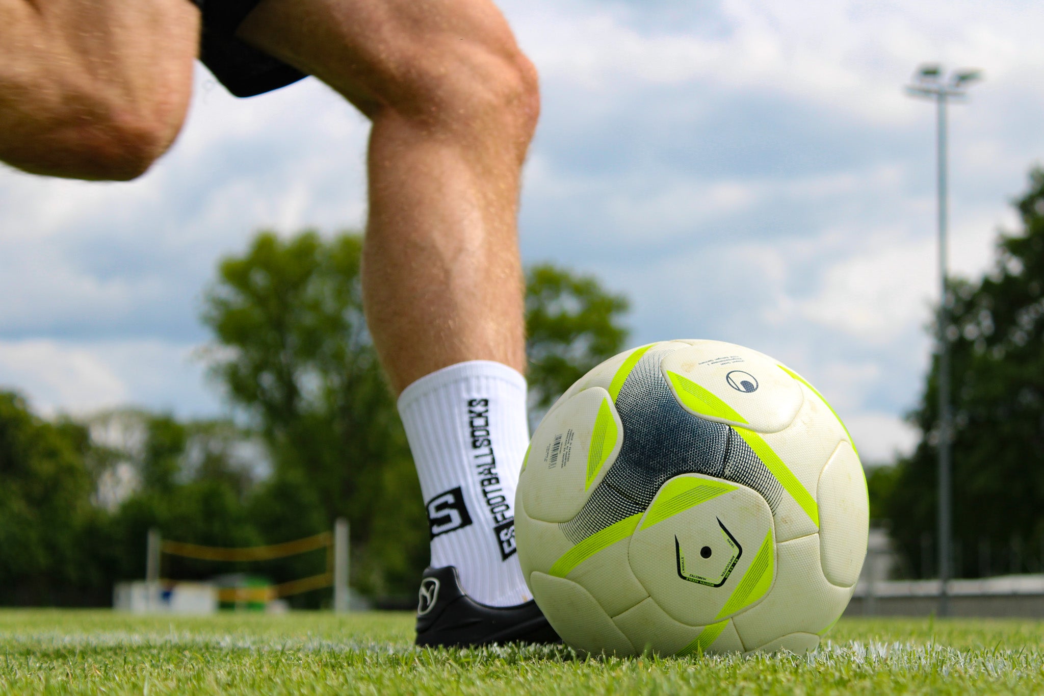 Bild von Schuss Bewegung beim Fußball- Ausholen, Spieler trägt Footballsocks. Auf Rasen aufgenommen mit Ball